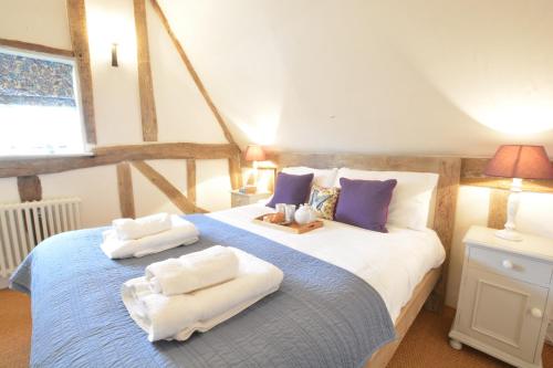 a bedroom with a bed with towels on it at The Cross Wing, High Ash Farm in Peasenhall