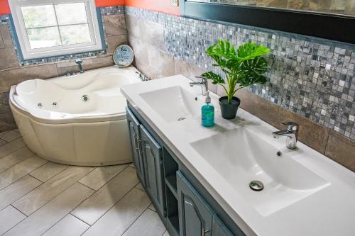a bathroom with a tub and a sink and a bath tub at Villa De Cruz - Presidential Suite in Scarborough