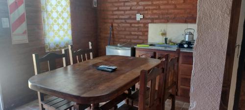 a kitchen with a wooden table with chairs and a sink at Cabañas La Gringa in Potrero de los Funes