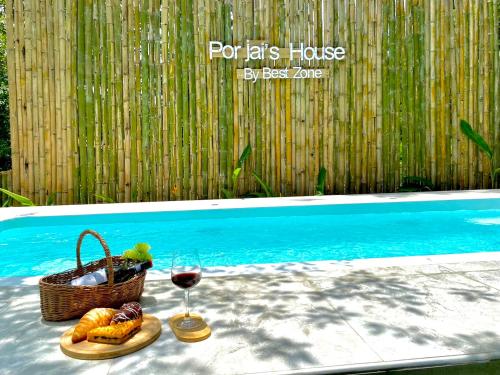 a basket of fruit and a glass of wine next to a pool at Por jai’s House in Campson