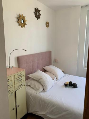 a bedroom with a white bed with a pink headboard at La Maison de la Plage in Trouville-sur-Mer