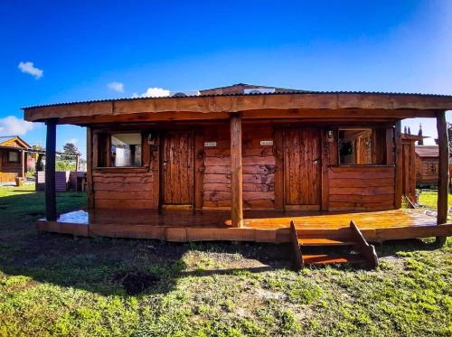 eine Holzhütte mit einem Dach auf dem Rasen in der Unterkunft La Cabaña de Sofi in Tandil
