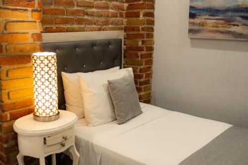a bedroom with a white bed with a brick wall at Hotel Boutique ADAZ in Santa Marta