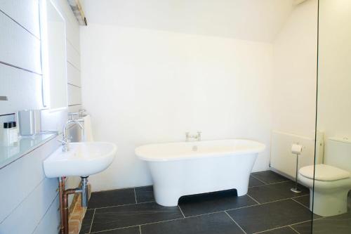 uma casa de banho com uma banheira, um lavatório e um WC. em The Seed Store, High Ash Farm em Peasenhall