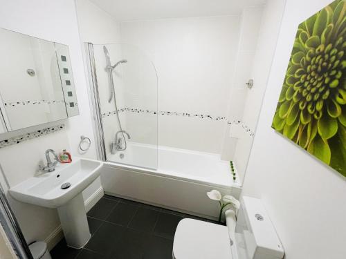 uma casa de banho branca com um lavatório e um chuveiro em Flat 3 - Seabreeze - 2 bedrooms em Southbourne