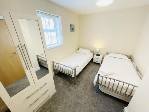 Duas camas num pequeno quarto com um espelho em Flat 3 - Seabreeze - 2 bedrooms em Southbourne
