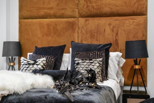 een bed met zwart-witte kussens en 2 lampen bij Platinum Gold Court Modern Apartment in Kent
