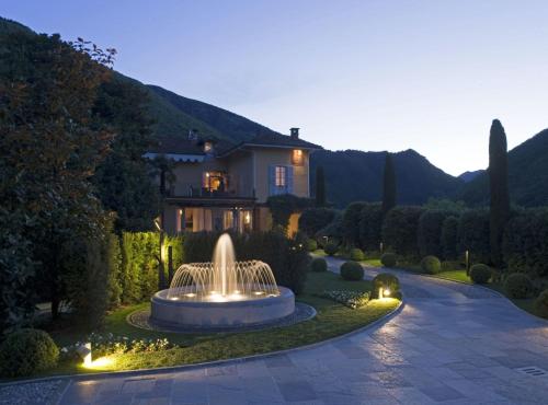 a house with a fountain in the middle of a yard at Park Hotel Villa Belvedere in Cannobio