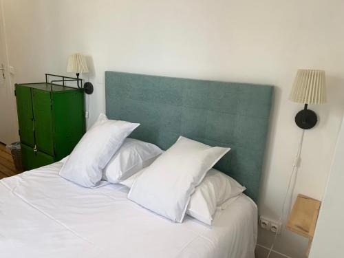 a white bed with a green headboard and white pillows at La Maison de la Plage in Trouville-sur-Mer