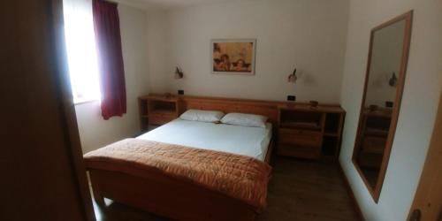 een kleine slaapkamer met een bed en een spiegel bij Plodar èscht in Sappada