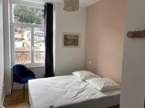 a bedroom with a bed and a window and a chair at Les balcons du Sancy - Appartement neuf 3 étoiles in Le Mont-Dore
