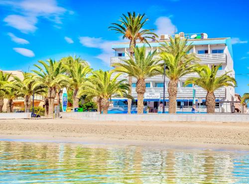 a hotel on the beach with palm trees and water at Hotel Neptuno in San Pedro del Pinatar