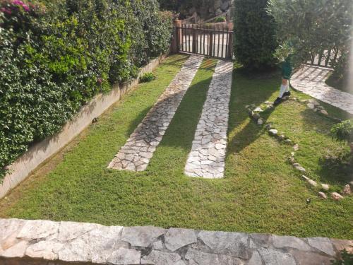 维拉西米乌斯Casa Pepe Confortevole villetta con giardino a 2 min dal mare的一个人走过有石头小路的花园