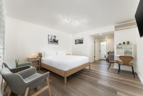 a bedroom with a white bed and two chairs at The Franciscan Hotel in Santa Barbara