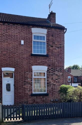 a brick house with a fence in front of it at Victorian Semi Detached House behind the High Street in Newton in Makerfield