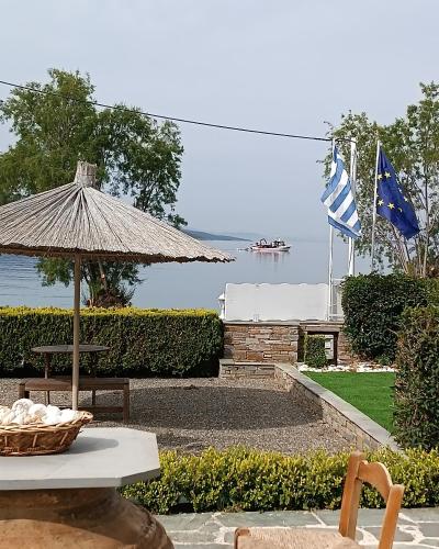 a picnic table with an umbrella and flags on the water at Enigma Boutique Houses Vraxos in Marmarion