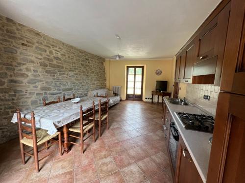 a kitchen with a table and a stone wall at Appartamenti Gli Ippocastani in San Benedetto Belbo
