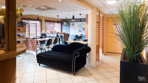 a lobby with a black chair and a counter at Hotel First Rodez in Rodez