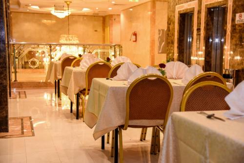 un comedor con mesas y sillas con mantel blanco en Plaza Inn Ohud Hotel, en Medina