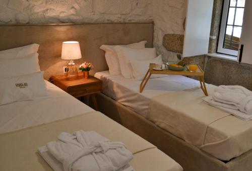 a room with two beds and a table with a lamp at Casa do Theatro Guest House in Barcelos