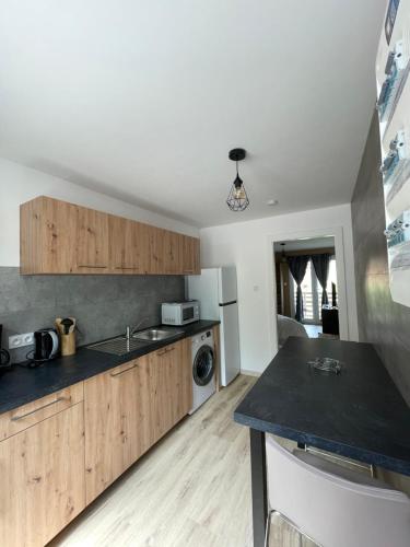 une cuisine avec des armoires en bois et un comptoir noir dans l'établissement Les gîtes de la bergerie, à Xonrupt-Longemer