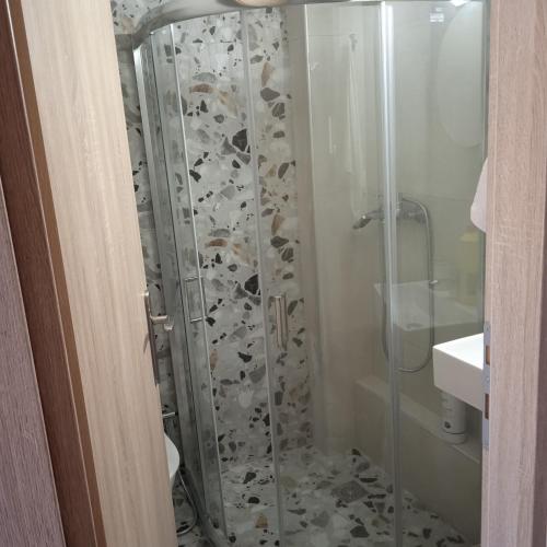 baño con ducha y puerta de cristal en Porto Athos 0, en Nea Roda