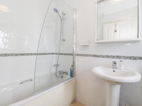 uma casa de banho branca com um lavatório e um chuveiro em The Coach House em Carnforth