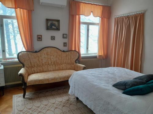 um quarto com uma cama, uma cadeira e janelas em Källgård em Lohja
