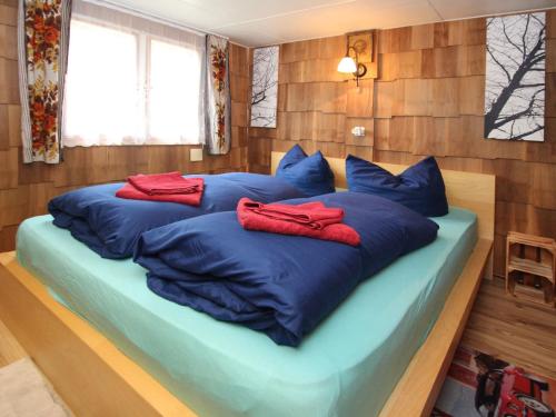 un grande letto blu con cuscini rossi sopra di Bungalow Wernsdorf a Wernsdorf