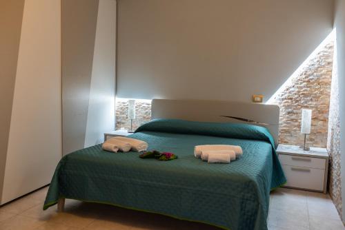 a bedroom with a green bed with towels on it at B&B al Vico Pepe in Castelmezzano