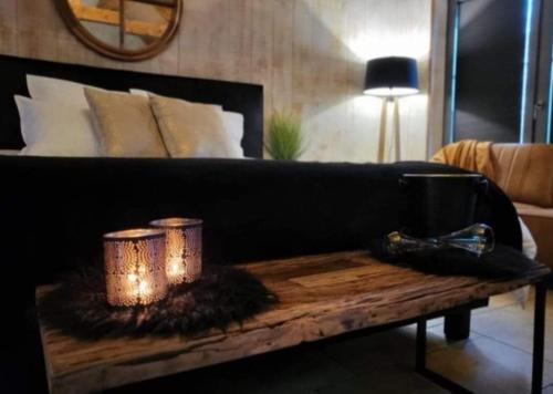 - un canapé noir avec deux bougies sur une table en bois dans l'établissement Levasion nature, à Beauraing