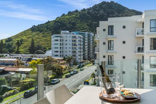 a table with a bottle of wine on a balcony with a city at Luxury at the Caymans in Mount Maunganui
