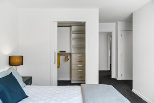 a white bedroom with a bed and a dresser at Luxury at the Caymans in Mount Maunganui