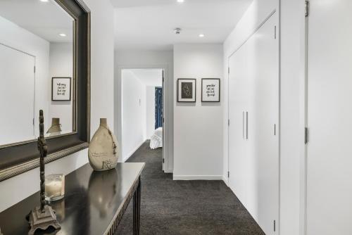 a hallway with white walls and a mirror at Luxury at the Caymans in Mount Maunganui