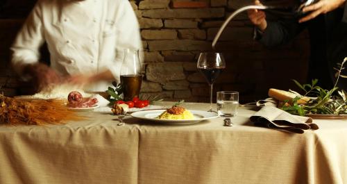a table with a plate of food and a man in the background at Relais San Maurizio in Santo Stefano Belbo