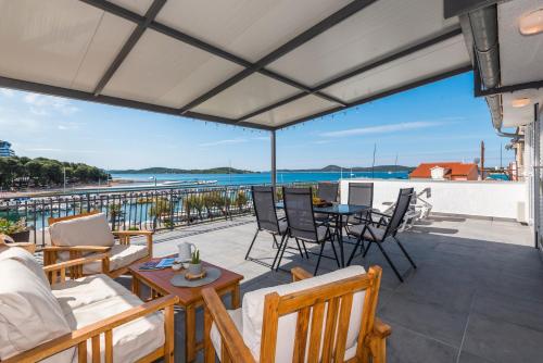 a patio with chairs and tables and a view of the water at Apartment and Rooms Dalmatiko in Vodice