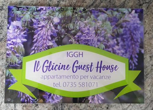 IGGH Il Glicine Guest House في سان بنيديتّو ديل ترونتو: علامة أمام حفنة من الزهور الأرجوانية