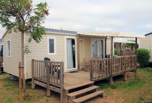 a large wooden deck on a tiny house at Mobil home vue mer camping Tohapi in Vias