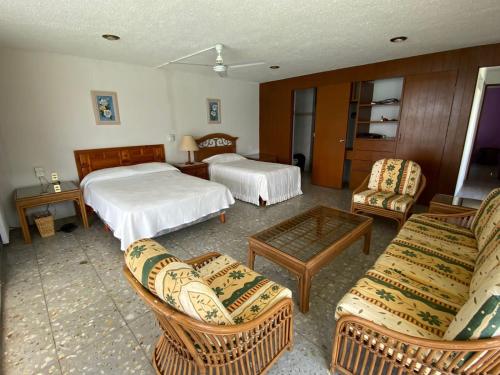 Habitación de hotel con 2 camas, sofá y sillas en Bella casa a la orilla del lago & estacionamiento en Tequesquitengo
