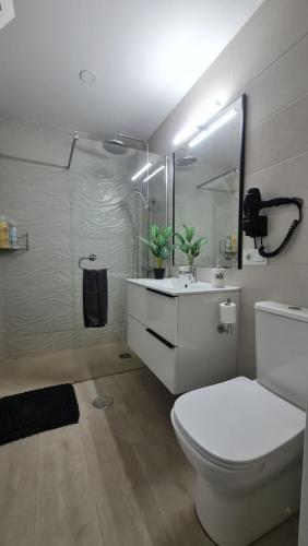 a white bathroom with a toilet and a sink at TREBOL Apartamentos Benalmádena in Arroyo de la Miel