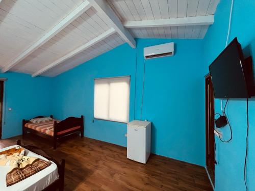 um quarto com paredes azuis e uma cama e uma televisão em Favela Chic Room em Durrës