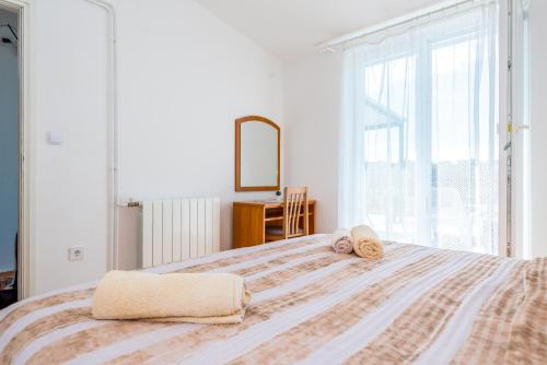 a bedroom with a large bed with towels on it at Apartment and Rooms Dalmatiko in Vodice