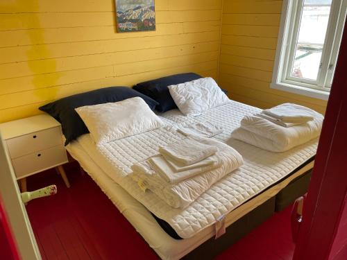 a bed with white sheets and towels on it at Kræmmervika Rorbuer - Rustic Cabins & Hostel in Lofoten in Ballstad