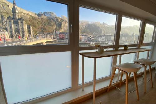 a room with windows and a table and two stools at L'Essentiel in Dinant