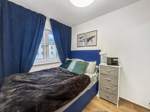 a bedroom with blue curtains and a bed with a dresser at Comfortable 2 Bedroom Flat In The City Centre in Edinburgh