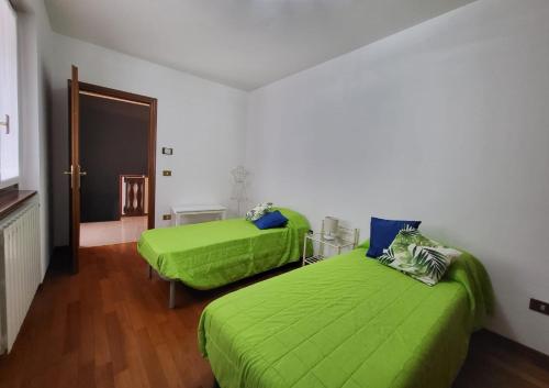 2 camas en una habitación con sábanas verdes en Casa la GlorioSa, en Gravellona Toce