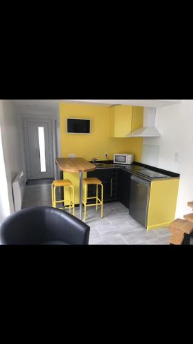 una cucina con armadi gialli, tavolo e sedie di Le 30 a Canteleu