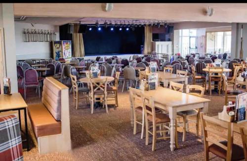 a dining room with tables and chairs and a stage at Coopers Beach 3-Bed Caravan Sleeps 8 & Pets Ok in Colchester