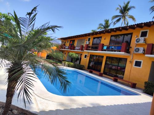 una piscina frente a un edificio con palmeras en Hotel J.B. en Zihuatanejo