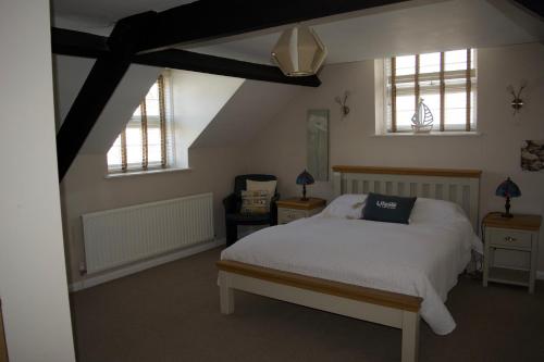 a bedroom with a white bed and two windows at Coach House. Falcon Mews in Bude